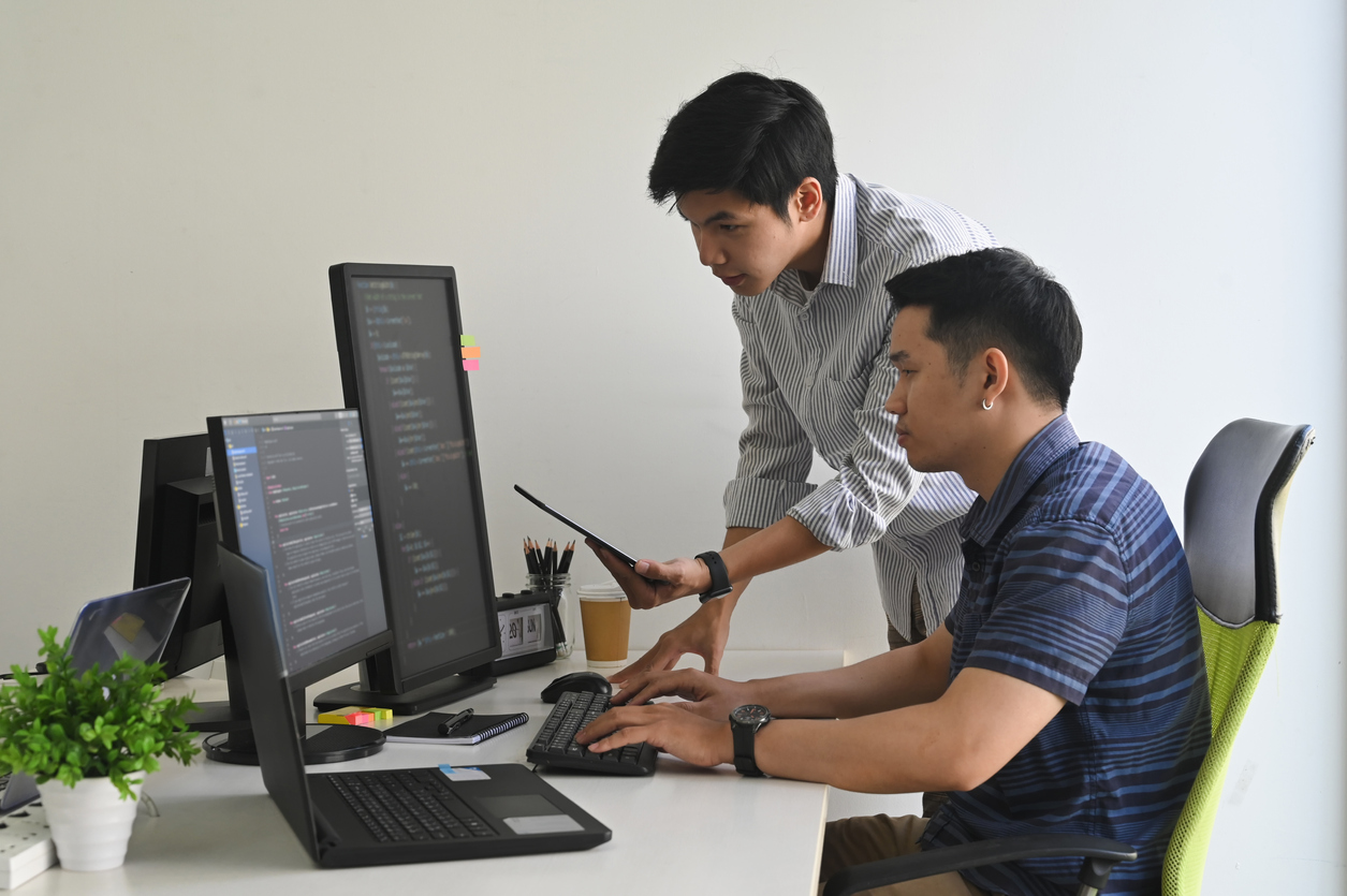 Young programmers working on computer and tablet in modern office workplace. Integrate with BigCommerce